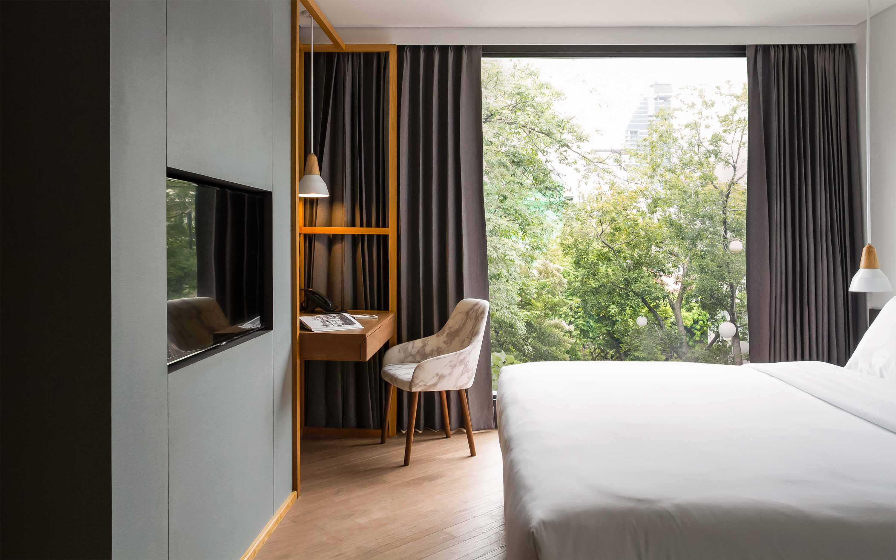 King size bed and lush green view in the Deluxe Room at Volve Hotel Bangkok